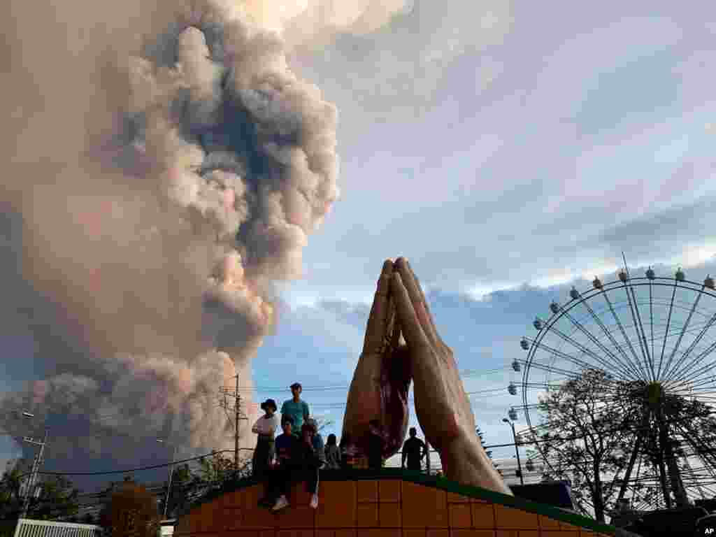 People watch as the Taal volcano spews ash and smoke during an eruption in Tagaytay, Cavite province south of Manila, Philippines on Sunday. Jan. 12, 2020. 