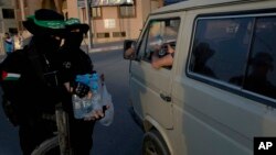 Masked Hamas gunmen give out water to motorists in Gaza City just minutes before breaking fast, during the Muslim holy month of Ramadan, May 16, 2019. 