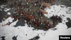 Umat Hindu memuja dewa Matahari di sungai Yamuna yang tercemar, saat berlangsugnya festival keagamaan Chhath Puja di New Delhi, India, 10 November 2021. (REUTERS/Adnan Abidi)