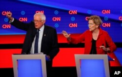 FILE - Sen. Bernie Sanders, I-Vt., and Sen. Elizabeth Warren, D-Mass., talk during in the first of two Democratic presidential primary debates hosted by CNN in the Fox Theatre in Detroit, July 30, 2019.