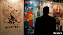 FILE - A visitor looks at posters of productions of China International TV Corporation at "Filmart," a part of Entertainment Expo Hong Kong. 