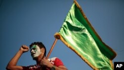 FILE - A supporter of Shiite rebels, known as Houthis, holds a green flag with Arabic writing reading, 'At your order, oh messenger of Allah,' during a celebration of Muhammad's birth in Sanaa, Yemen, in October 2020.