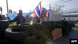 Anti-government protesters wave national flags as they block intersection during rally in Bangkok, Jan. 13, 2014.