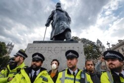 Police officers stand in front of the Winston Churchill statue during a rally in Parliament Square in London, Tuesday, June 9, 2020. The rally is to commemorate George Floyd whose private funeral takes place in the US on Tuesday.