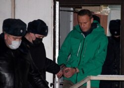 FILE - Opposition leader Alexei Navalny is escorted out of a police station on Jan. 18, 2021, in Khimki, outside Moscow, following the court ruling that ordered him jailed for 30 days.