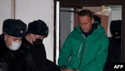 Opposition leader Alexei Navalny is escorted out of a police station on Jan. 18, 2021, in Khimki, outside Moscow, following the court ruling that ordered him jailed for 30 days.