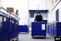 An employee of Cryonomic, a Belgium company producing dry ice machines and containers which will be used for COVID-19 vaccine transportation, pushes a medical dry ice container in Ghent, Dec. 2, 2020.