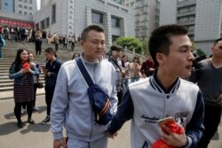 FILE - Sun Wenlin, right, and his partner Hu Mingliang leave the court after a judge ruled against them in China's first gay marriage case in Changsha in central China's Hunan province, April 13, 2016.