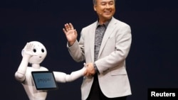 SoftBank Corp. Chief Executive Masayoshi Son (R) waves with the company's human-like robots named 'pepper' during a news conference in Urayasu, east of Tokyo June 5, 2014. 