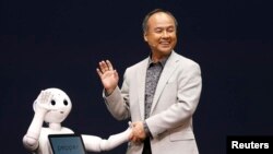 SoftBank Corp. Chief Executive Masayoshi Son (R) waves with the company's human-like robots named 'pepper' during a news conference in Urayasu, east of Tokyo June 5, 2014. 