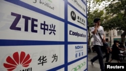 资料照片：一名中国男子从武汉街头有着华为和中兴标徽的广告牌前走过。（2012年10月11日）