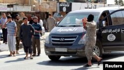 An Islamic State militant uses a loud-hailer to announce to residents of Tabqa city that Tabqa air base has fallen to Islamic State militants, in nearby Raqqa city, Syria, Aug. 24, 2014.