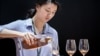 FILE - This picture taken on May 27, 2014 shows a woman pouring a glass of cognac at Vinexpo Asia Pacific in Hong Kong. 