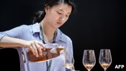 FILE - This picture taken on May 27, 2014 shows a woman pouring a glass of cognac at Vinexpo Asia Pacific in Hong Kong. 