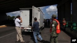 Para petugas imigrasi memeriksa bagian belakang truk kargo untuk mencari migran ilegal di pos perbatasan di Tapachula, Chiapas, Meksiko, 7 Juni 2019. (Foto: AP)