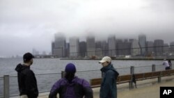 Three local residents stand at the East River in the Brooklyn borough of New York City after hurricane Irene, downgraded in the city to a tropical storm, passed through, August 28, 2011