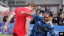 Le Brésilien Ronaldinho (D) et le Russe Dmitry Bulykin lors d'un match amical à St. Petersburg le 21 mai 2017.