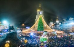 Kerumunan orang merayakan Tahun Baru di sekitar pohon Natal dengan latar belakang Katedral St. Sofia di Kyiv, Ukraina, Jumat dini hari, 1 Januari 2021. (Foto: AP)