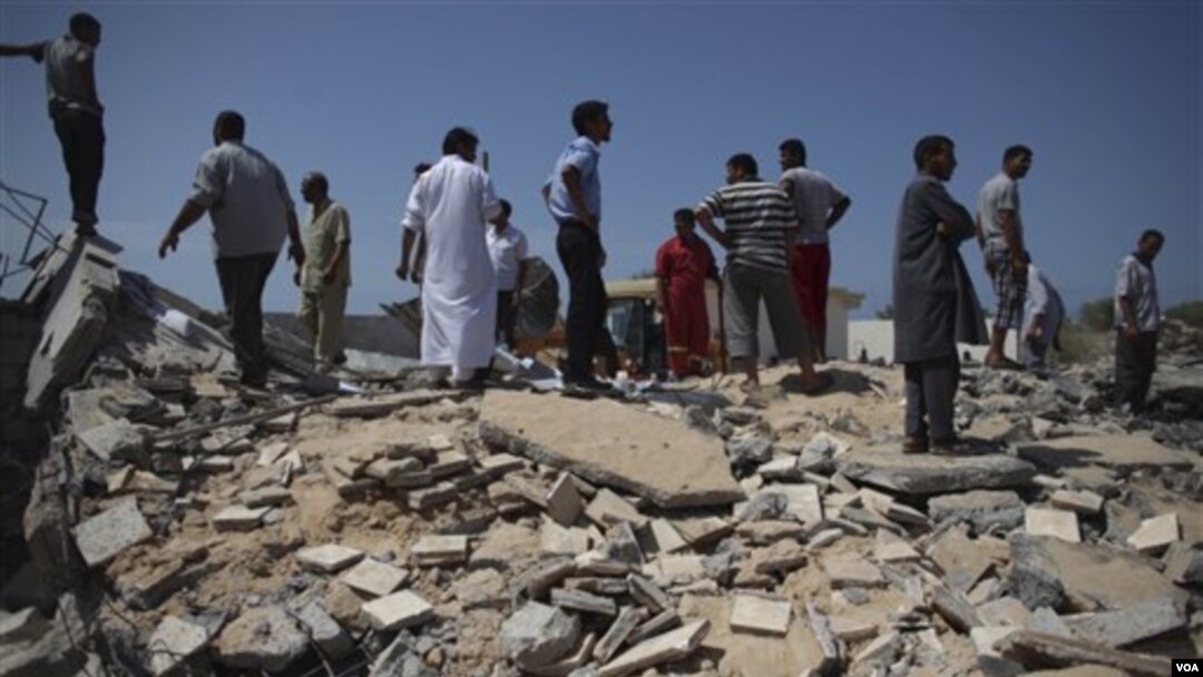Para pejabat Libya menunjukkan bekas sebuah klinik yang hancur di kota Zlitan, sebelah timur Tripoli, Senin (25/7).