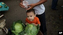 A man, accompanied by a boy, counts bills at the San Isidro market in Tegucigalpa. (file)