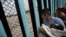 A member of the Central American migrant caravan, holding a child, looks through the border wall toward a group of people gathered on the U.S. side, as he stands on the beach where the border wall ends in the ocean, in Tijuana, Mexico, April 29, 2018. 