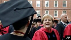 Kanselir Jerman, Angela Merkel, menyambut mahasiswa Harvard yang tengah diwisuda saat ia berjalan dalam prosesi lewat Harvard Yard d awal acara wisuda, 30 Mei 2019, di Cambridge, Mass. (foto: AP Photo/Steven Senne)