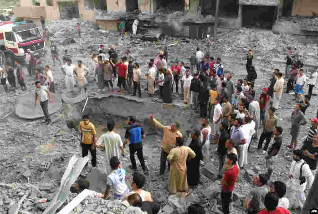 People gather around a crater at the scene of an explosion in the northern Syrian city of Raqqa, early on August 7, 2013. 