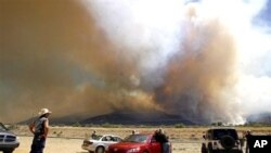 People watch the growing plume of smoke from across Highway 92 as the Monument Fire burns in the Huachuca Mountains near Sierra Vista, Arizona, June 14, 2011