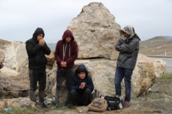 FILE - A group of Afghan migrants rest on a main road after crossing the Turkey-Iran border near Dogubayazit, Agri province, eastern Turkey, April 11, 2018.