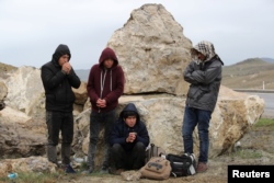 FILE - A group of Afghan migrants rest on a main road after crossing the Turkey-Iran border near Dogubayazit, Agri province, eastern Turkey, April 11, 2018.