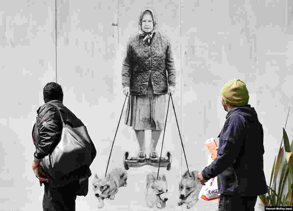 Pedestrians look at a new mural depicting Britain&#39;s Queen Elizabeth II that is spray-painted onto the external wall of a house in south-east London.