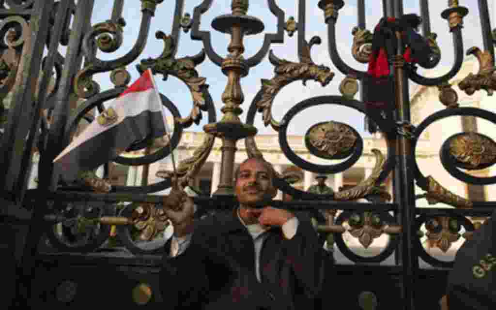 An anti-government protester gestures as he sits outside the Egyptian Parliament in Cairo, Egypt, Wednesday, Feb. 9, 2011. Around 2,000 protesters waved huge flags outside the parliament, several blocks from Tahrir Square, where they moved a day earlier i