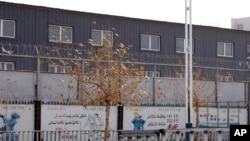 Two layers of barbed wire fencing ring the "Hotan City apparel employment training base" where Hetian Taida has a factory in Hotan in western China's Xinjiang region, Wednesday, Dec. 5, 2018. 