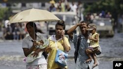 Thai residents carry children across flooded streets in Bangkok, Thailand, November 6, 2011.