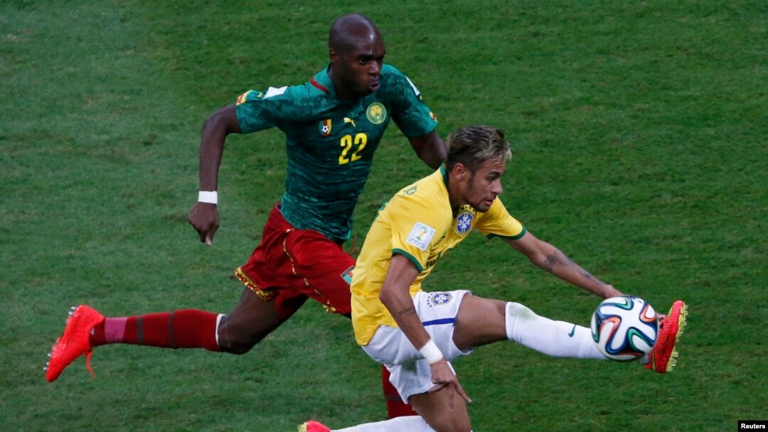 Pemain Kamerun Allan Nyom mengejar Neymar dari Brazil dalam pertandingan di stadion nasional Brasilia (23/6). 