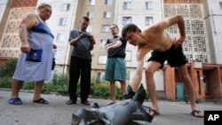 Local residents display fragment of a shell after overnight shelling in Donetsk, eastern Ukraine, Friday, Aug. 8, 2014.