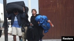 Una caravana de miles de habitantes de América Central que intentan llegar a los Estados Unidos carga sus pertenencias durante el cierre del refugio Barretal en Tijuana, México.