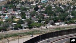 FILE - A residential neighborhood of Juarez, Mexico, and U.S. Border Patrol vehicles on both sides of a border fence as seen from El Paso Texas, on April 22, 2020. 