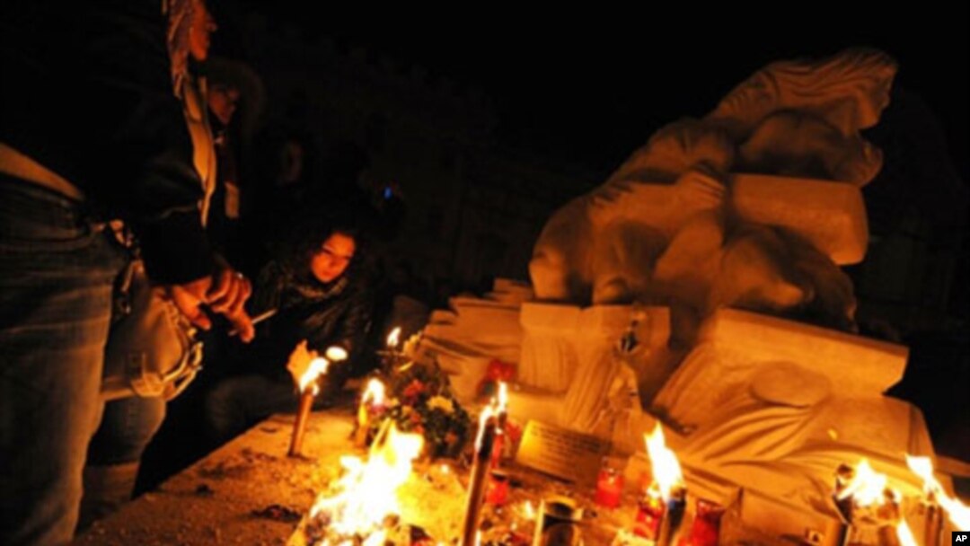 People pray near a statue in honor of quake victims during a candle rally in L'Aquila on 06 Apr, 2010, to commemorate the first anniversary of the major earthquake which struck the area