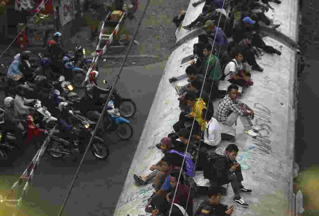 Penumpang KRL duduk di atas kereta. Kabel berarus listrik yang mengerakkan kereta ini, berada tak jauh di atas kepala mereka.