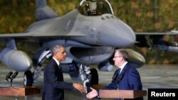 El presidente Barack Obama estrecha la mano a su homólogo polaco, Bronislaw Komorowski, con el fondo de un avión caza F-16.