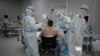 FILE - Medical workers in protective suits treat a patient (not the author of this story) infected with the coronavirus, at a makeshift hospital set up at the Sokolniki Exhibition and Convention Center in Moscow, Russia, Nov. 9, 2020. 