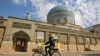 Seorang pria Irak mengendarai sepedanya melewati masjid yang tertutup di tengah restriksi yang diberlakukan pemerintah untuk menekan penyebaran virus COVID-19 di Baghdad, 19 Februari 2021. (Foto: AHMAD AL-RUBAYE / AFP)