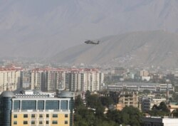 FILE - A NATO helicopter flies over the city of Kabul, Afghanistan.