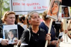 A woman holds a victim's picture as she marches with other women denouncing violence against women, on the opening day of a multiparty debate on domestic violence, in Paris, Sept. 3, 2019.