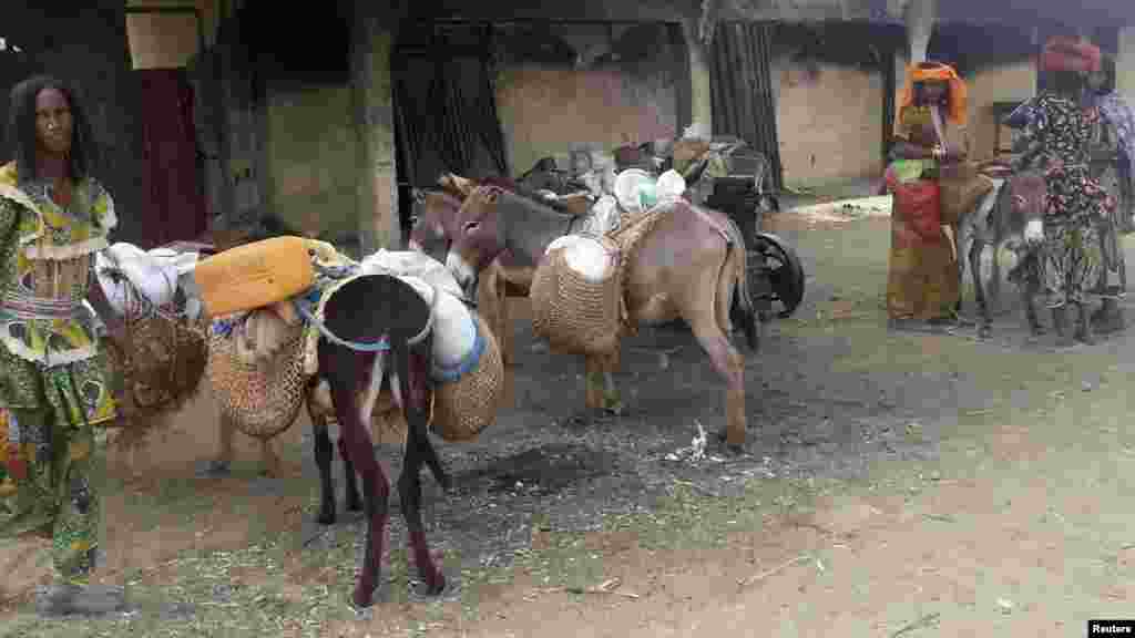 Women load the rest of their belongings on donkeys, following an attack in Kawuri January 28, 2014.