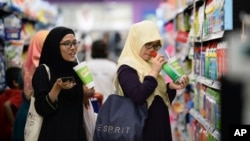 FILE - Malaysian women chat as they shop at a mall in Petaling Jaya outside Kuala Lumpur, Malaysia, Oct. 30, 2014.