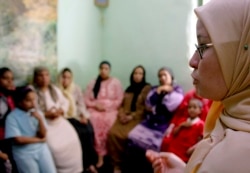 FILE - A counselor talks to a group of women to try to convince them that they should not have female genital mutilation performed on their daughters, in Minia, Egypt, June 2006.