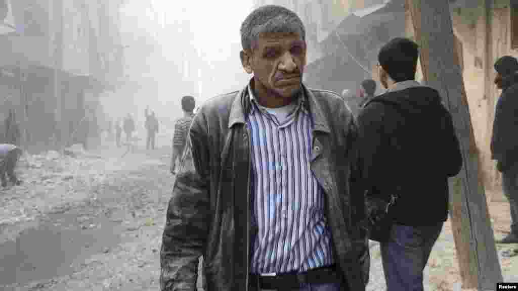 A man walks at a site hit by what activists said was a barrel bomb dropped by forces loyal to Syria's President Bashar al-Assad in Aleppo's al-Shaar district, Feb. 9, 2014. 