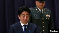 Japan's PM Shinzo Abe attends a flag return ceremony to mark the return of the Japan Self-Defense Force troops stationed with the UN Disengagement Observer Force in Golan Heights, at the Defense Ministry in Tokyo, January 20, 2013.